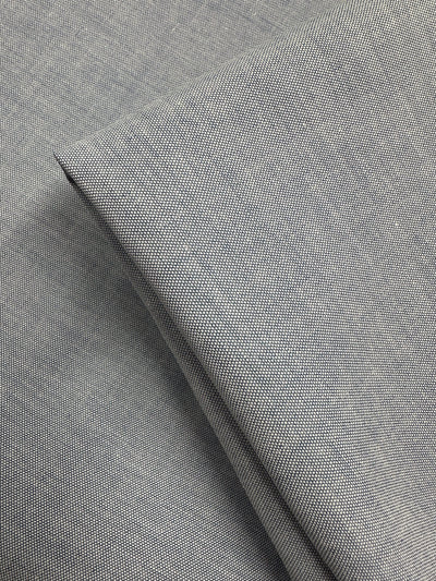 Close-up of Super Cheap Fabrics' Oxford Cotton - Denim (146cm): light gray fabric with fine woven texture, neatly folded to highlight its smooth, detailed weave and enhanced cotton softness.