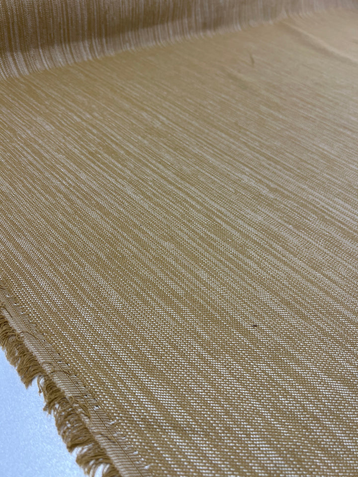 Close-up of a piece of Super Cheap Fabrics Upholstery Twill - Caramel - 147cm with a subtle linen texture. The edges are slightly frayed, and the Upholstery Twill - Caramel is draped out flat with the surface clearly visible, showcasing the weave and texture.