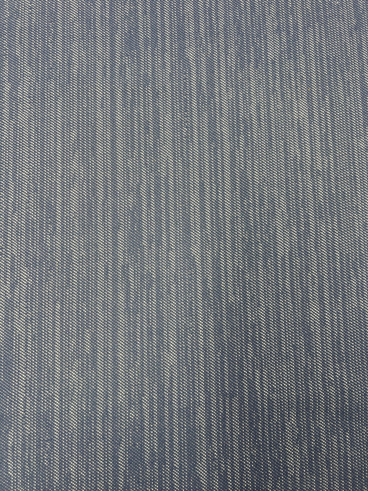 A close-up view of a blue and white fabric with a subtle linear pattern. The durable fabric has thin, vertical white lines evenly spaced across a blue background, creating a textured and slightly woven appearance, ideal for furniture upholstery. This is the Upholstery Twill - Lavendar Blue - 147cm from Super Cheap Fabrics.