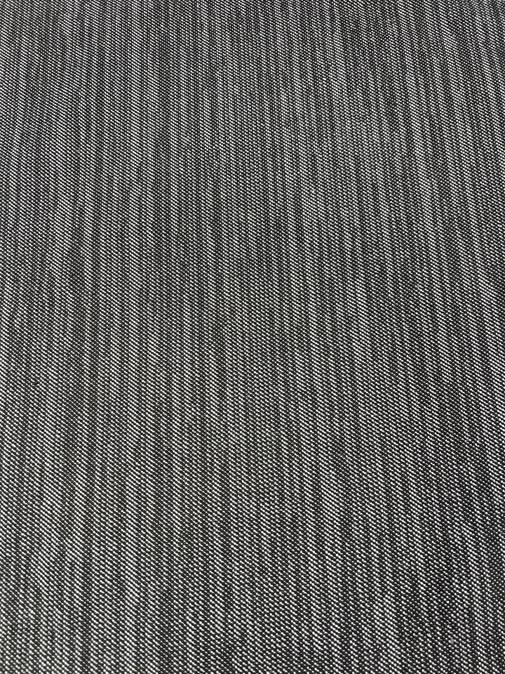 Close-up image of a textured fabric with a uniform pattern, ideal for furniture upholstery. The black and white weave creates a subtle checkerboard appearance. The texture is slightly coarse, suggesting the durable fabric might be Upholstery Twill - Salt & Pepper - 147cm from Super Cheap Fabrics.