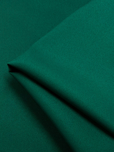 A close-up of a folded piece of Twill Suiting - Ultramarine Green - 153cm from Super Cheap Fabrics with a slight sheen. The smooth, tightly woven texture showcases fine, subtle diagonal lines characteristic of twill suiting. The fabric is neatly arranged to highlight its material and quality.