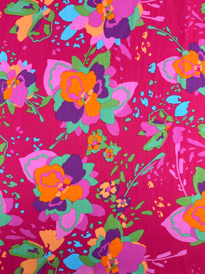 Super Cheap Fabrics’ Printed Linen Blend - Wild Fuchsia (145cm) features bold abstract flowers in orange, purple, pink, and green on a magenta base with blue accents—ideal for vibrant upholstery or standout summer jackets.