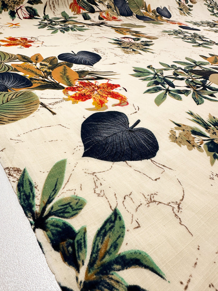 Printed Linen Blend - Botanic Sketch by Super Cheap Fabrics features a lightweight beige fabric with bold black leaves, green foliage, and orange flowers. At 148cm wide, it's perfect for summer jackets and laid out flat for detail.