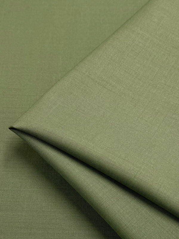 A close-up photo of a piece of Super Cheap Fabrics' Merino Wool Suiting - Hunter Green - 155cm, neatly folded. The material appears smooth and has a subtle, even texture. The fabric’s soft, muted green color is consistent throughout the image, highlighting its luxurious texture and excellent breathability.