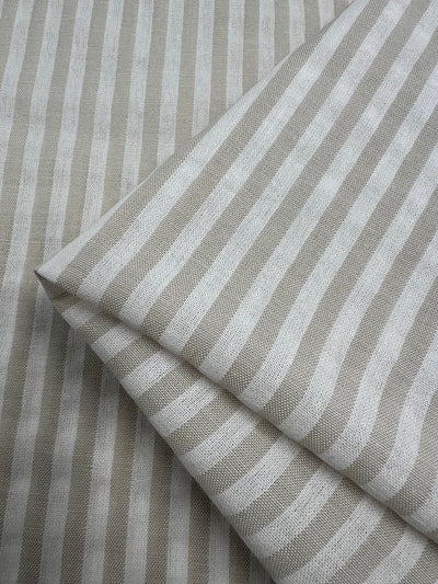 Folded Linen Cotton - Arctic Wolf Stripe - 145cm from Super Cheap Fabrics. The pattern features vertical alternating stripes of light beige and off-white, creating a classic and clean look. Made from natural fibers, this lightweight fabric has a soft, woven texture.