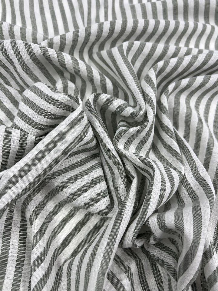 Wrinkled white and gray striped fabric, made from durable Super Cheap Fabrics Linen Cotton - Alfalfa Stripe - 145cm, with the stripes running vertically. The natural fibers are gathered and folded in various places, creating a textured and slightly chaotic appearance.