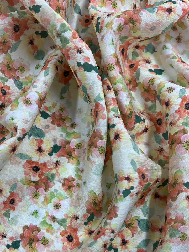 A close-up view of Designer Cotton - Geranium - 145cm by Super Cheap Fabrics with a vibrant floral pattern. The multi-colour design features an array of flowers in shades of pink, orange, and yellow, supplemented by green leaves on a light background, perfect for adding charm to your home decor.