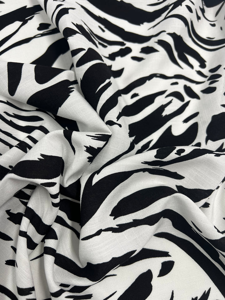 A close-up of Designer Bamboo Rayon - Liquid Zebra - 147cm by Super Cheap Fabrics. The material is slightly crumpled, showcasing the abstract striped pattern which adds depth and texture to the image, making it a versatile choice for those seeking vibrant prints.