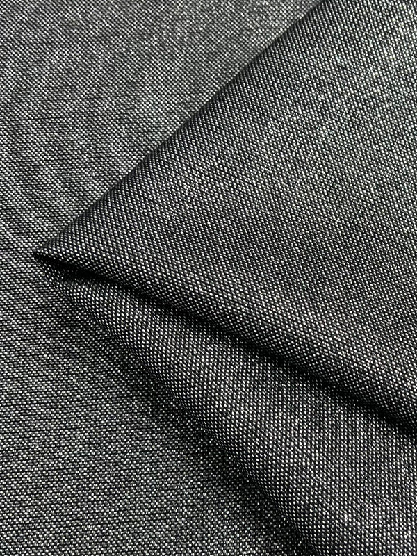 A close-up of dark gray fabric with a visible weave pattern. The Wool Lamé - Metallic - 150cm by Super Cheap Fabrics appears to be folded diagonally, showcasing its texture and thickness. The material has a slightly shiny, speckled appearance, indicating a blend of fibers.