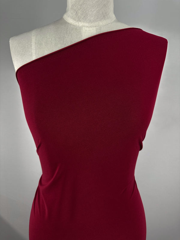 A torso mannequin showcases a fitted, one-shoulder dress made from Super Cheap Fabrics’ ITY Knit - Red Bud (150cm), featuring medium weight and a smooth feel, set against a plain gray background.