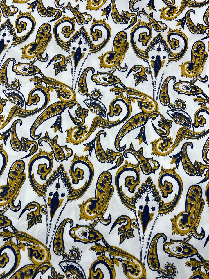 A 100% cotton fabric with an intricate paisley pattern in shades of navy blue, mustard yellow, and black on a white background. Ideal for household décor, the design features elegant swirling shapes and floral motifs, creating a detailed, visually rich texture in light weight fabric. Introducing Cotton Sateen - Paisley Swirl - 140cm by Super Cheap Fabrics.