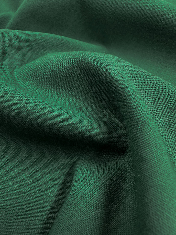 Close-up of the Ramie Linen - Hunter Green fabric by Super Cheap Fabrics, showcasing its soft and slightly textured surface with gentle folds. Made from natural fibers, it presents a smooth and luxurious appearance.