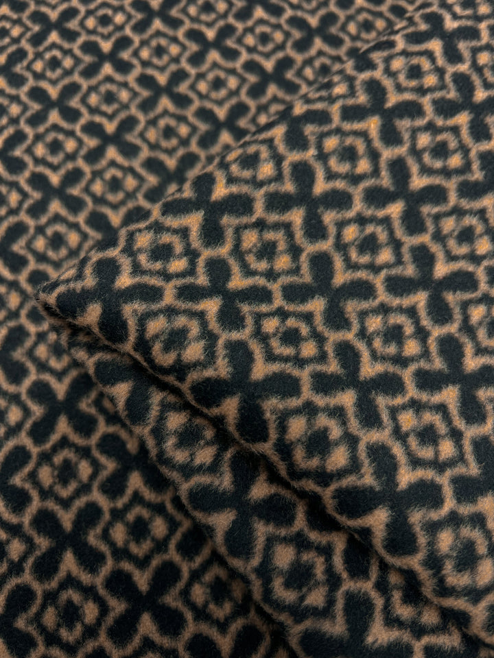 Close-up of a heavy weight fabric with a geometric pattern featuring interlocking diamond shapes. The design is in contrasting shades of dark blue and beige. Made from a wool polyester blend, the **Super Cheap Fabrics Designer Wool - Mosaic - 150cm** fabric appears to be folded, highlighting the texture and complexity of the pattern. Dry clean only.