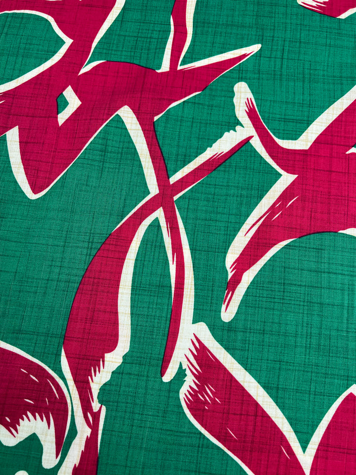A vibrant fabric design featuring abstract red bird-like shapes with white outlines on a green background. This lightweight Bamboo Rayon - Dance Pepper Green - 150cm from Super Cheap Fabrics is perfect for home decor, with birds in various dynamic poses creating an energetic and lively pattern.