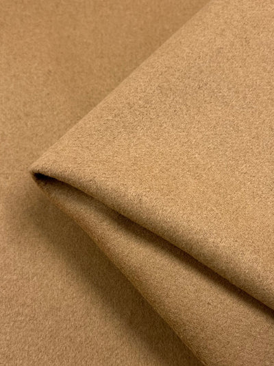 A close-up of a neatly folded piece of Wool Cashmere - Brown Sugar - 150cm by Super Cheap Fabrics. The texture appears to be soft and smooth, with slightly visible fibers. This medium weight fabric is layered, showing one folded edge, giving a sense of its thickness and quality – perfect for outer coats.