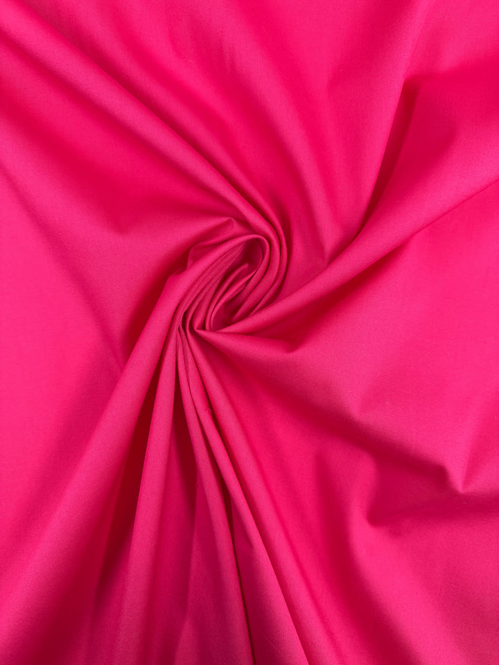 Super Cheap Fabrics’ Plain Cotton - Fuchsia - 150cm features vibrant fuchsia cotton, artfully gathered at the center for a twisted, swirling effect with smooth, radiating folds.