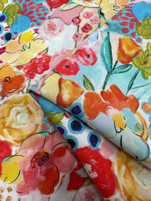 A close-up of brightly colored floral fabric with overlapping patterns of yellow, red, pink, blue, and green flowers. The Super Cheap Fabrics Designer Rayon - Festive - 145cm features a mix of pastel and vibrant hues, creating a lively and cheerful design. Some folds add texture to the versatile fabric.