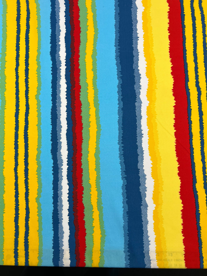 A Deluxe Print - Beachside - 155cm from Super Cheap Fabrics is a colorful polyester fabric with vertical stripes in various widths. The uneven stripes feature a mixture of bright shades, including blue, yellow, red, green, and white. Some have jagged edges, giving this vibrant designer fabric a dynamic appearance perfect for versatile uses.
