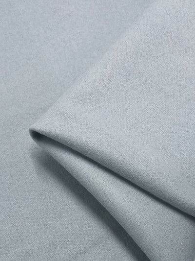 A close-up view of folded Wool Cashmere - Dawn Blue - 150cm fabric by Super Cheap Fabrics, showcasing its soft and smooth texture. The material appears to be heavy weight wool cashmere fabric that drapes easily.