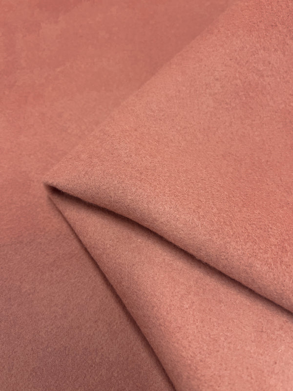 Close-up of Super Cheap Fabrics' Wool Cashmere - Cameo Brown - 150cm with a soft, velvety texture. The fabric is slightly folded at the center, creating gentle, natural creases that add depth and dimension to the image. Sustainably sourced and limited in stock, its smooth and uniform color enhances its luxurious appeal.