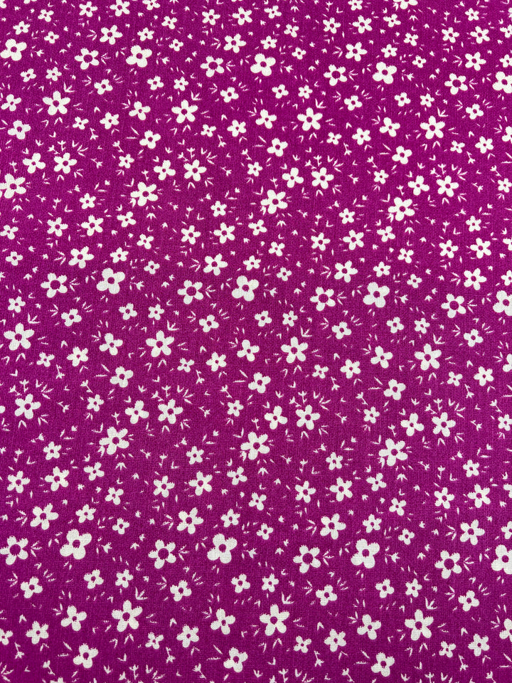 A lightweight fabric with a vibrant magenta background featuring a dense pattern of small white flowers. The flowers vary slightly in shape and size, creating a lively and intricate floral design that's perfect for beginner-friendly sewing projects. This is the Bamboo Rayon - Pink DaisyRain - 145cm from Super Cheap Fabrics.