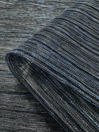 A close-up of a piece of Metallix Pleat - Cobalt Metal fabric from Super Cheap Fabrics, featuring a lightweight, shimmering ribbed pattern in shades of navy and black across its 140cm width.