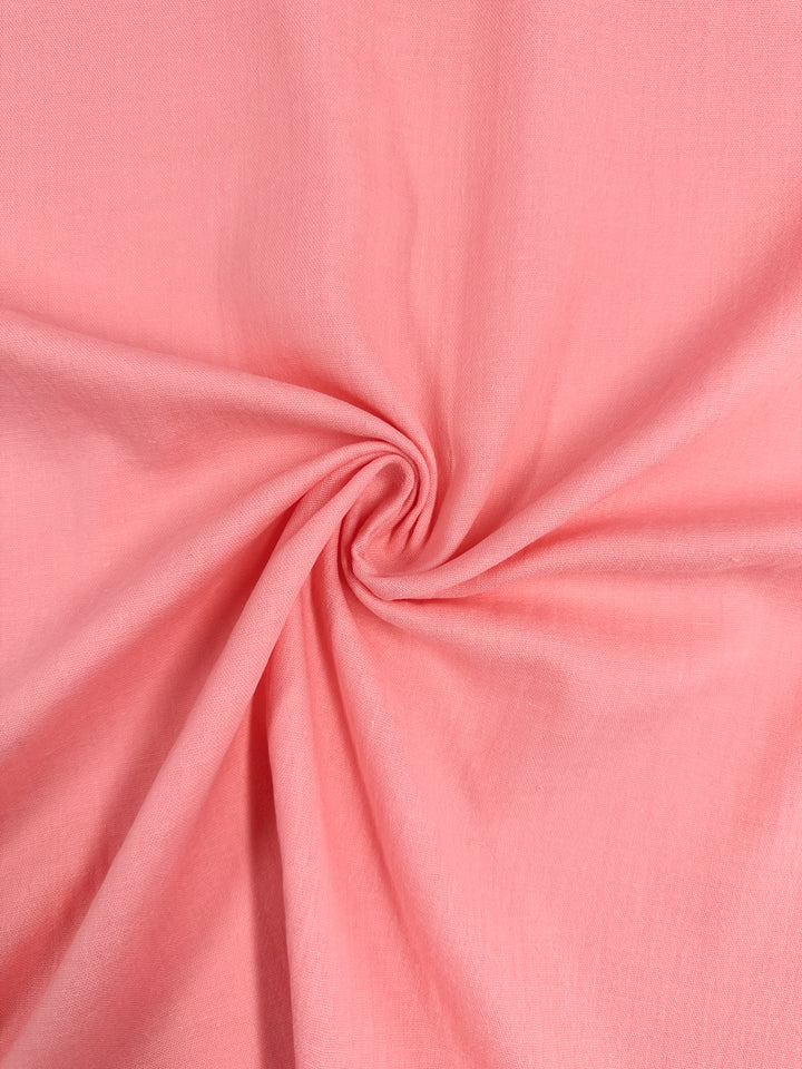 Close-up of the Muslin - Flamingo Pink - 145cm fabric from Super Cheap Fabrics. It has a smooth texture and is gathered in the center to create a spiral design, forming soft folds and radiating lines. This organic material appears lightweight with a slightly glossy finish.