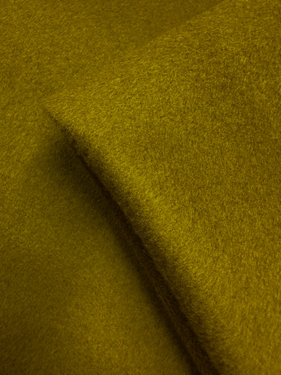 A close-up of Super Cheap Fabrics’ Wool Cashmere in Ecru Olive (150cm) showcases its premium, soft texture with a subtle diagonal fold across the surface.