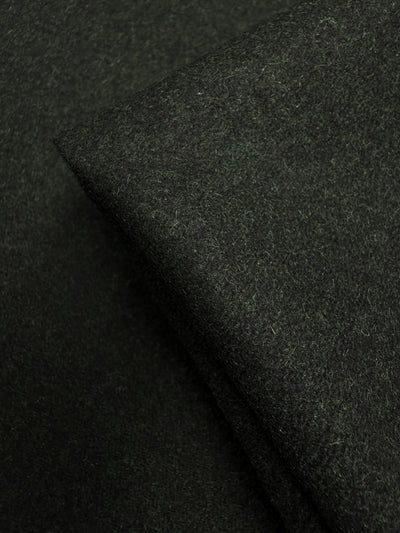 A close-up of two overlapping pieces of Super Cheap Fabrics’ Melton Wool - Rosin Marle (150cm), showcasing the soft, slightly fuzzy texture and rich dark green color typical of this heavyweight wool fabric.