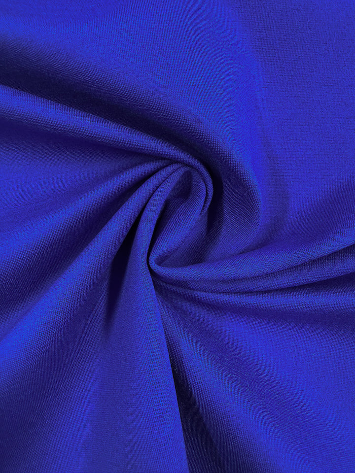 Close-up of Super Cheap Fabrics’ Milano Ponte in Dazzling Blue (160cm), featuring smooth, vibrant fabric gathered into a spiral pattern with soft folds and shadows.