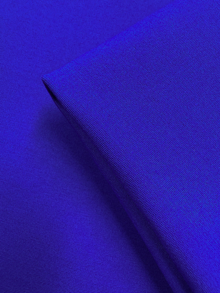 A close-up of Super Cheap Fabrics’ Milano Ponte in Dazzling Blue (160cm), featuring a folded section that highlights the smooth, fine texture and vibrant royal blue color of this heavyweight fabric.