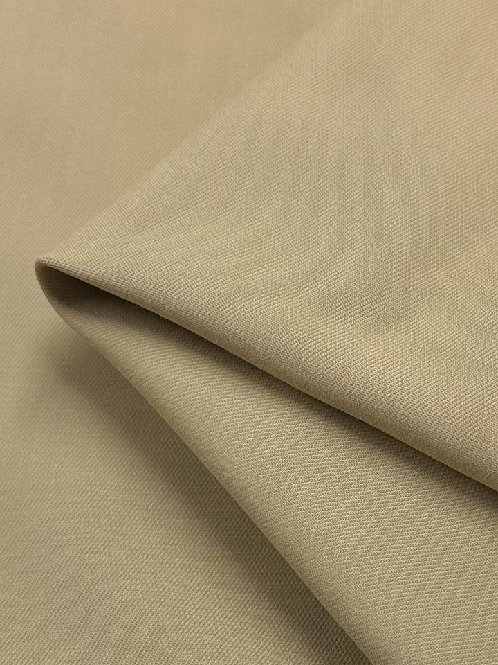 Close-up of the "Stretch Viscose Suiting - Pebble" by Super Cheap Fabrics, showcasing its beige texture and smooth surface with visible weave, emphasizing quality. Width: 130cm.