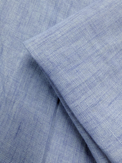 Close-up of Super Cheap Fabrics' Pure Linen - Washed Sky (142cm), featuring soft, subtle weave and gentle shading in light blue. The lightweight to medium fabric is shown neatly folded, highlighting its smooth texture.