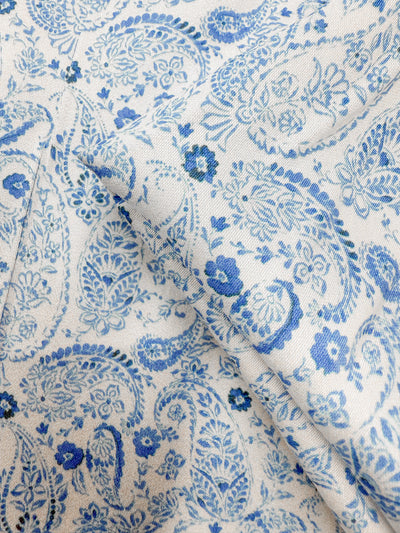 Close-up of Mercerised Rayon - Delft Vine (150cm) by Super Cheap Fabrics, featuring intricate blue paisley and floral patterns on lightweight, silky soft fabric with a smooth texture and detailed designs.