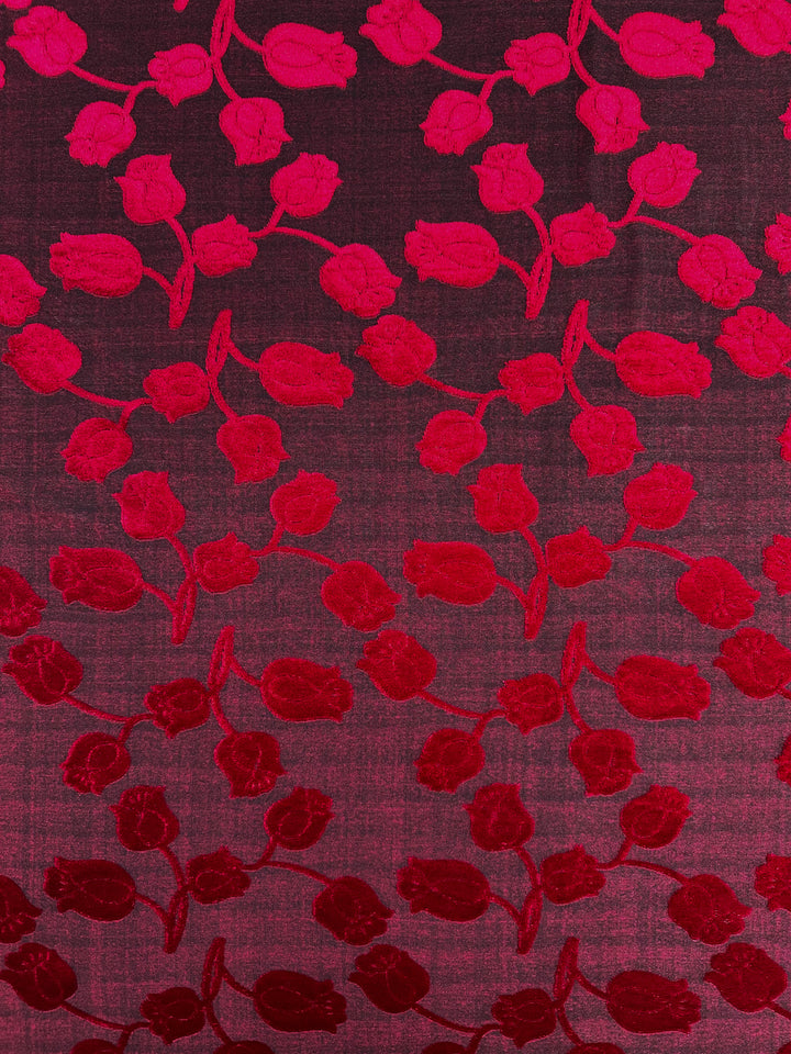 Super Cheap Fabrics' Burnout Velvet - Lychee (150cm) features a red and magenta floral pattern on a gradient background, transitioning from dark to light shades. The luxurious fabric showcases stylized flowers for an intricate and vibrant design.