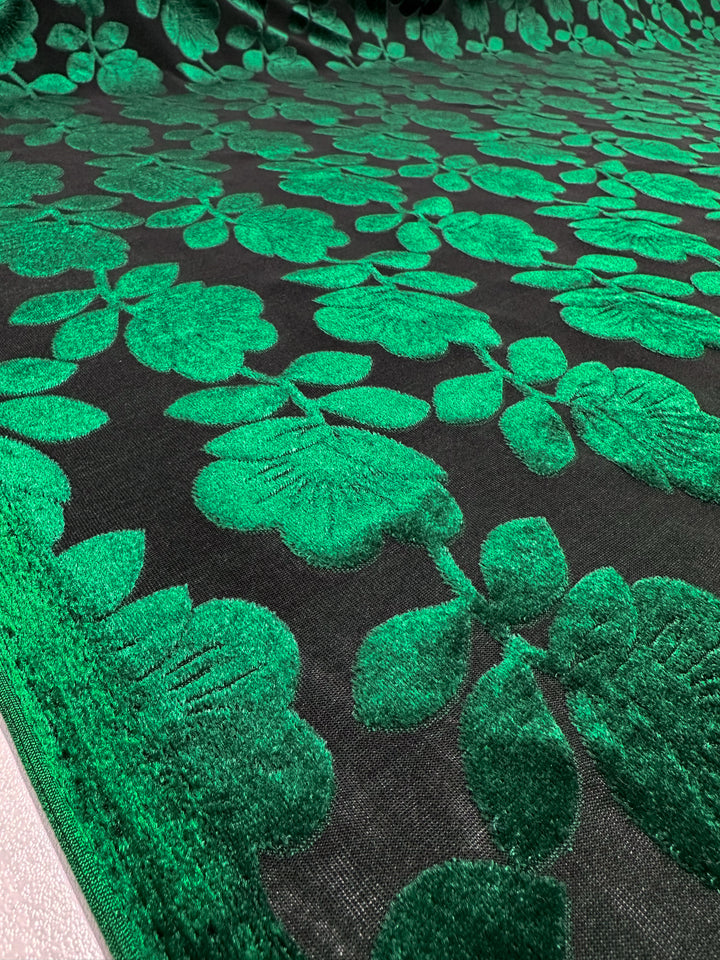 The "Burnout Velvet - Amazon - 150cm" by Super Cheap Fabrics showcases a luxurious, rich texture with bright green floral patterns on a dark background, exuding sophistication reminiscent of burnout velvet.