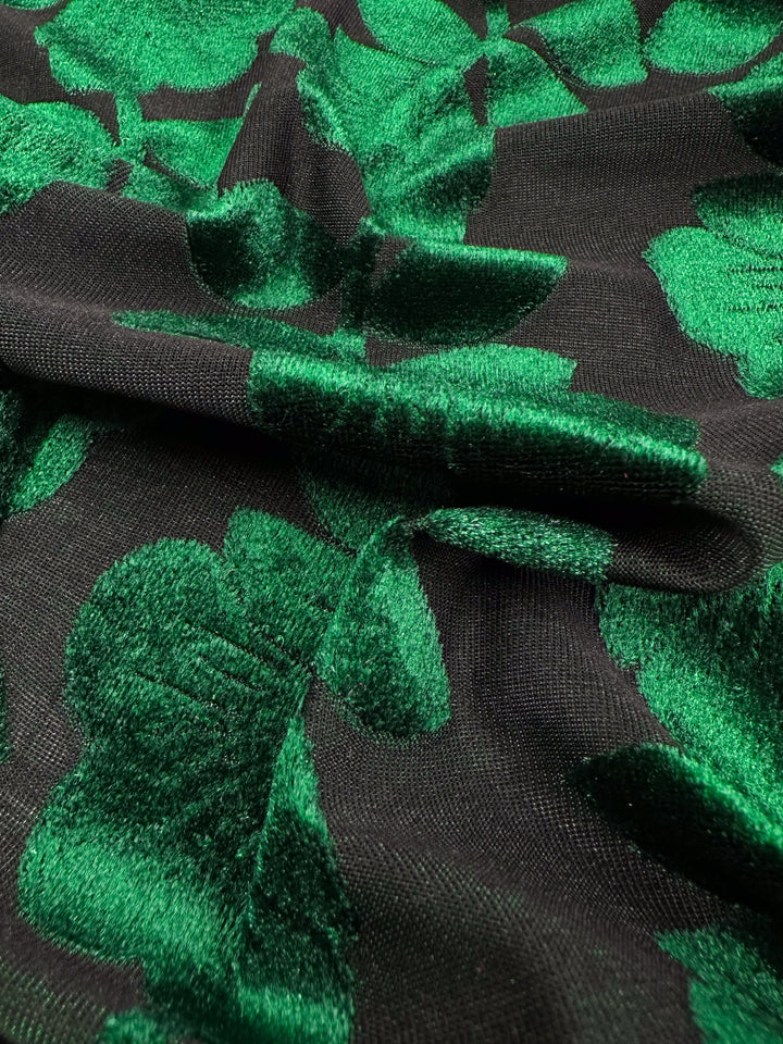 Close-up of the luxurious Burnout Velvet - Amazon by Super Cheap Fabrics, featuring an embossed green leaf pattern. The leaves' texture and sheen contrast elegantly with the matte background, creating a sophisticated and vibrant look. Width: 150cm.