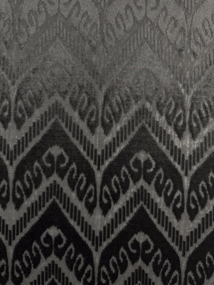 The Burnout Velvet - Arrows by Super Cheap Fabrics features a black and gray chevron and swirl pattern, reminiscent of an elegant evening gown, with a textured, symmetrical design.