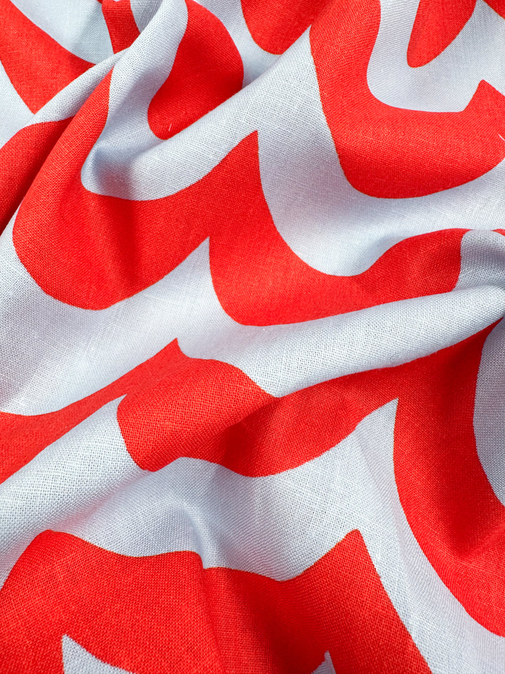 A close-up of Super Cheap Fabrics' Linen Blend - Smile - 136cm reveals bold Cherry Tomato and white wavy patterns. Slightly crumpled, the fabric's curves add texture, perfect for chic home decor with vibrant red popping against a crisp white background.