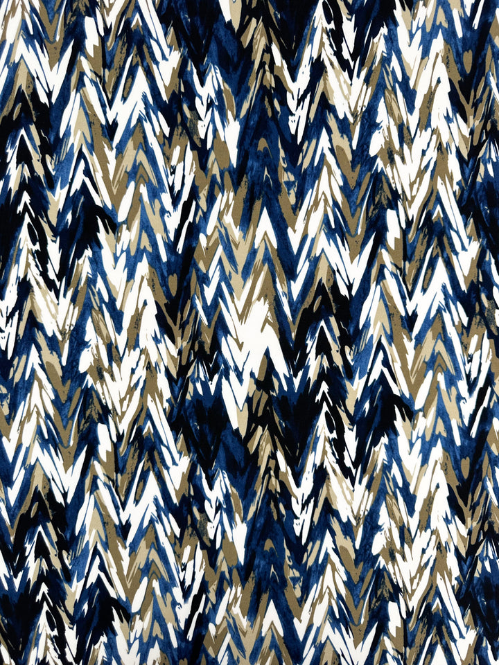 The Super Cheap Fabrics Printed Lycra - Arrows (150cm) features a medium-weight polyester/spandex blend with a brushstroke chevron pattern in navy blue, white, and brown. Its dynamic overlapping zigzag lines add abstract flair to any fabric project.