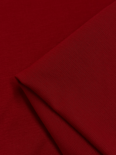 Close-up of a rich red waffle fabric with a smooth texture, showcasing subtle details in its weave. The image displays a neatly folded corner near the bottom left, emphasizing the material's softness and quality. The product shown is Waffle Knit - Fire - 152cm by Super Cheap Fabrics.
