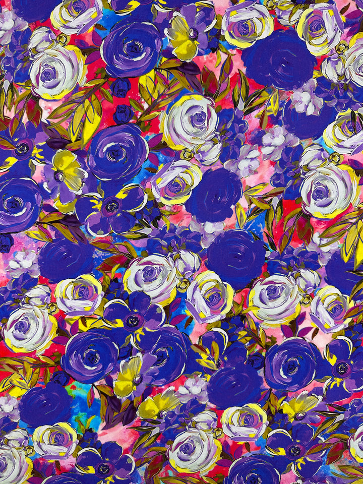 Super Cheap Fabrics' Designer Rayon - Zoe (145cm) boasts a vibrant floral pattern with bold purple and white roses, green leaves, and a lively pink, red, and blue backdrop. Its contrasting darker accents make it the perfect choice for fans of energetic prints.