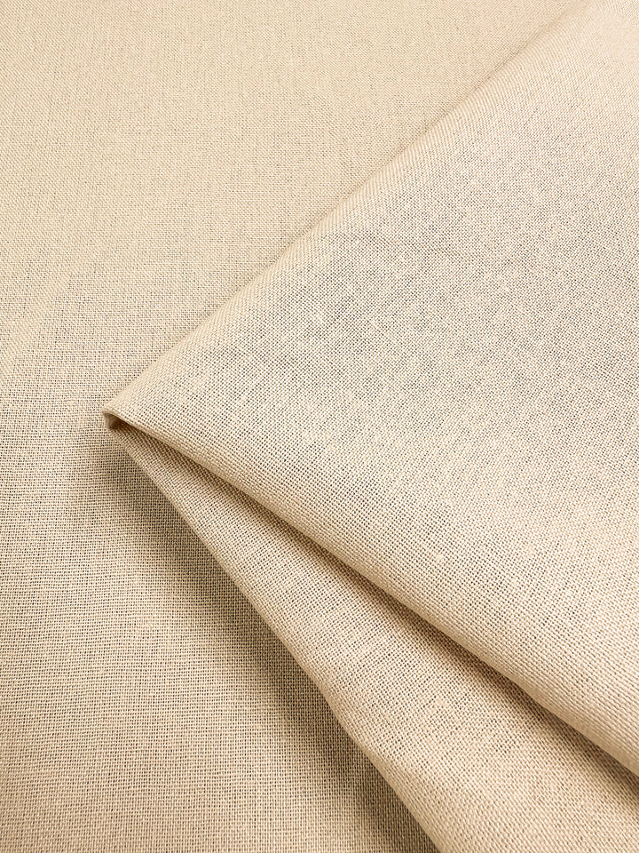 A piece of the Premium Linen Cotton - Shortbread from Super Cheap Fabrics, measuring 140cm and featuring a lightweight design with a subtle woven texture, is neatly folded at the corner to create a layered appearance.