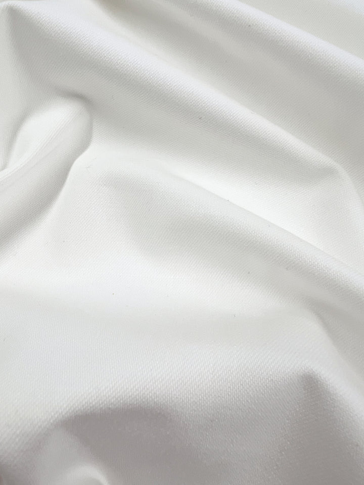 Close-up of Slubbed Linen Drill in Vanilla by Super Cheap Fabrics, showcasing its textured surface with soft folds and gentle draping. The fabric has a smooth, slightly shiny appearance, creating subtle shadows and highlights across its 140cm width.