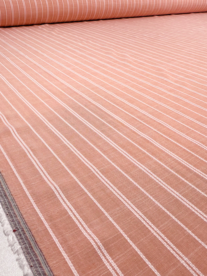 A close-up of Super Cheap Fabrics' Linen Blend - Dusty Blush Ticking (142cm), featuring soft pink fabric with evenly spaced thin white vertical stripes, laid out smoothly on a flat surface.
