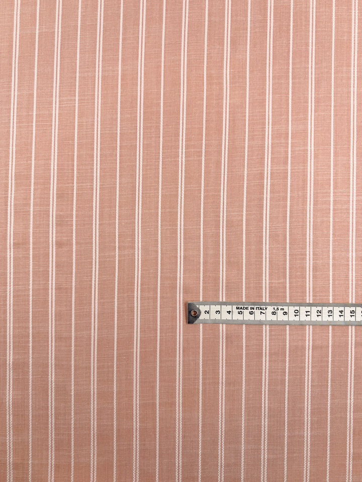 Super Cheap Fabrics' Linen Blend - Dusty Blush Ticking (142cm) is a lightweight, light brown linen fabric featuring evenly spaced vertical white stripes. Stripes run parallel to a centimeter-marked silver measuring tape at the bottom right.