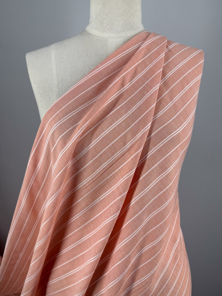 A dress form displays Super Cheap Fabrics' Linen Blend - Dusty Blush Ticking (142cm), a soft peach rayon-linen with fine white diagonal stripes, set against a plain gray background.