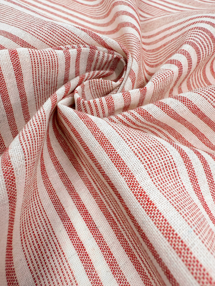 Super Cheap Fabrics’ Linen Blend - Rosebay Stripe - 145cm features alternating thin and thick red stripes on a cream background, perfect for lightweight upholstery with its textured, loosely gathered look.