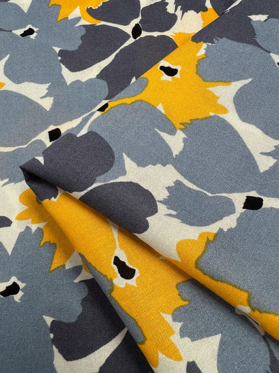 The Designer Rayon - Summer from Super Cheap Fabrics is a versatile, modern fabric featuring bold, abstract florals with large gray, yellow, and white flowers accented by black centers. This 140cm folded Rayon offers vibrant prints for a dynamic look.