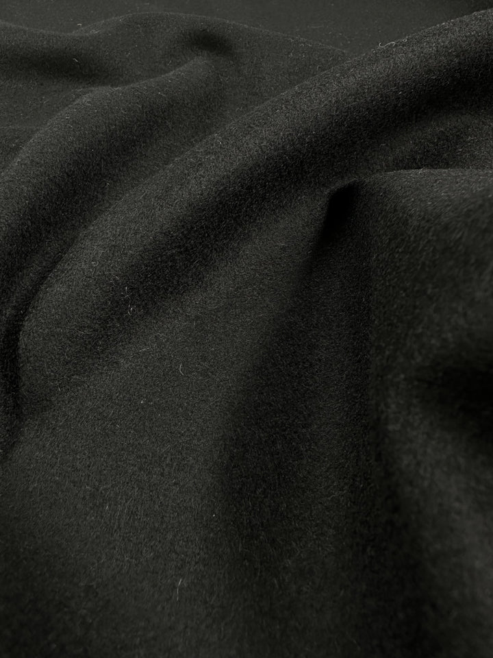 Close-up of Premium Virgin Wool fabric showcasing its luxurious texture and deep black color, emphasising the high-quality material.